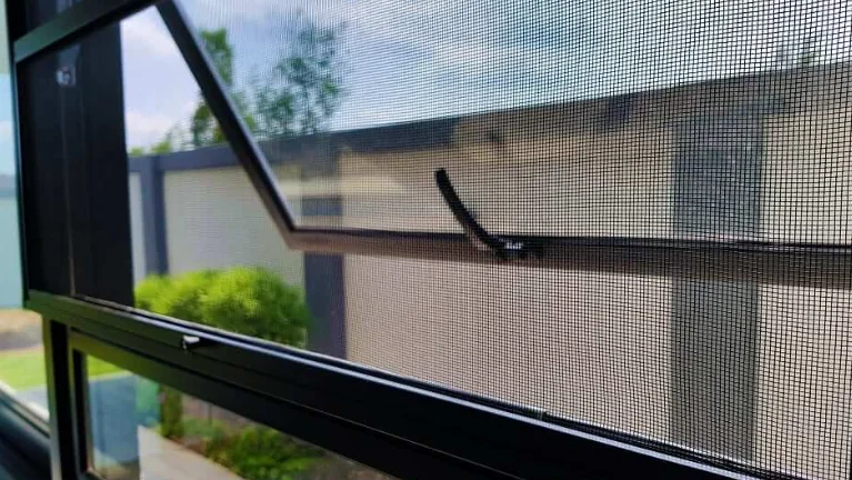 Mosquito net installed on sunny residential window with clear outdoor view